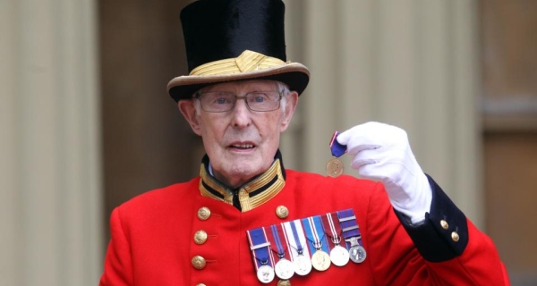 Pat Carroll poses with the medal he received from the queen for his 60 years of service at Buckingham Palace.